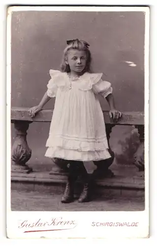 Fotografie Gustav Krenz, Schirgiswalde, Portrait kleines Mädchen im weissen Kleid an Geländer gelehnt