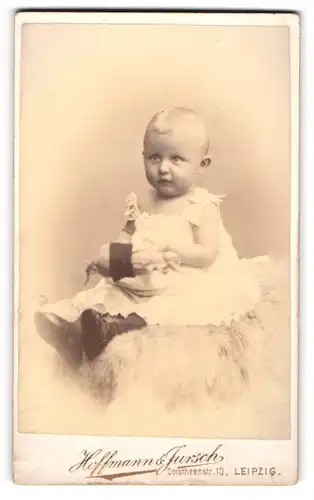 Fotografie Hoffmann & Jursch, Leipzig, Portrait kleines Mädchen im weissen Kleid auf Fell sitzend