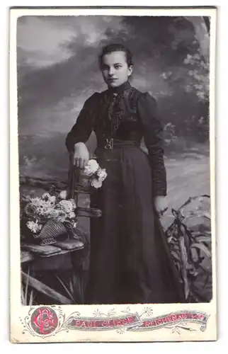 Fotografie P. Gliese, Reichenau i / S., Portrait junge Dame im schwarzen Kleid mit Blumen an Stuhl gelehnt