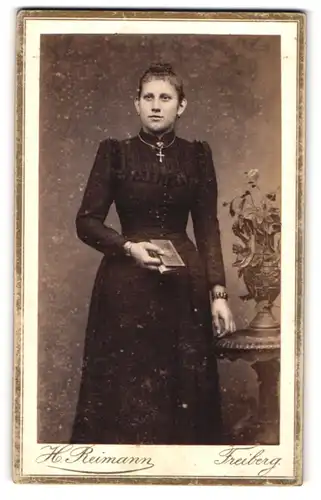 Fotografie H. Reimann, Freiberg, Portrait elegante Dame mit Kreuzkette und Buch in der Hand