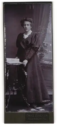 Fotografie Fritz Hacker, Annaberg i. S., Portrait hübsche junge Frau im Rüschenkleid am Tisch stehend