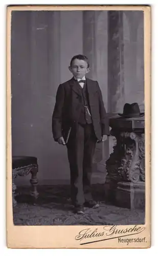 Fotografie Julius Grusche, Neugersdorf, Portrait halbwüchsiger Knabe im Anzug mit Fliege und Buch