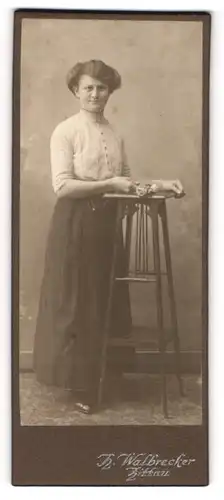 Fotografie H. Walbrecker, Zittau, Portrait modisch gekleidete Dame mit Blume an Tisch gelehnt