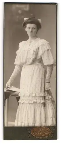 Fotografie E. Schuffert, Borna, Portrait junge Dame im gepunkteten Kleid mit Buch an Tisch gelehnt