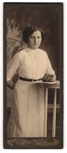 Fotografie Atelier Güttges, Zittau i / Sa., Portrait junge Dame in weisser Bluse mit Büchlein an Tisch gelehnt