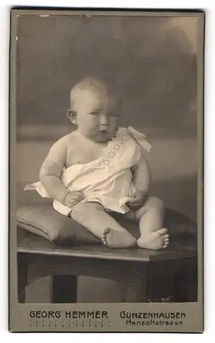 Fotografie Georg Hemmer, Gunzenhausen, Portrait niedliches Kleinkind im weissen Hemd auf Kissen sitzend