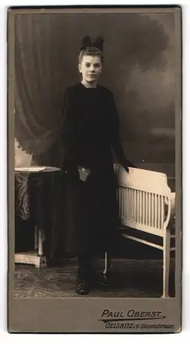 Fotografie Paul Oberst, Oelsnitz i. V., Portrait junge Dame im schwarzen Kleid an Bank gelehnt