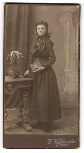 Fotografie H. Walbrecker, Zittau, Portrait modisch gekleidete Dame mit Buch an Tisch gelehnt