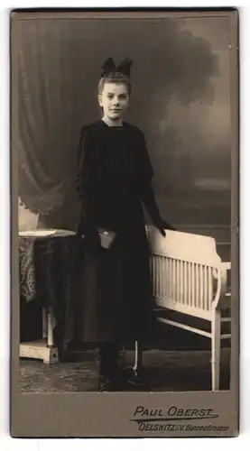 Fotografie Paul Oberst, Oelsnitz i. V., Portrait junge Dame im schwarzen Kleid an Bank gelehnt