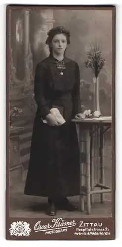 Fotografie Oscar Krämer, Zittau, Portrait junge Dame im schwarzen Kleid an Tisch gelehnt