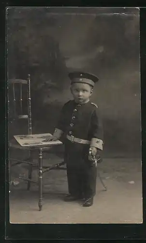 Foto-AK Baby Soldat steht neben einem Stuhl in Uniform