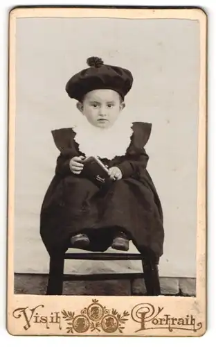 Fotografie Visit Portrait, Ort unbekannt, Portrait niedliches Kleinkind mit Mütze und Geldbörse in den Händen