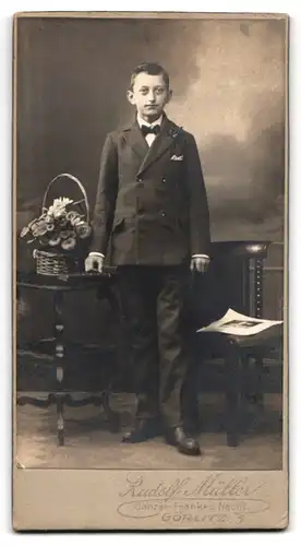 Fotografie Rudolf Müller, Görlitz, Portrait niedlicher Bube im hübschen Anzug neben einem Blumenkorb stehend