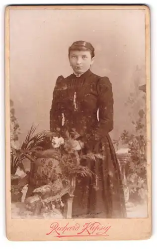 Fotografie Richard Klepsig, Hildesheim, Portrait bürgerliche Dame mit Blume an Stuhl gelehnt