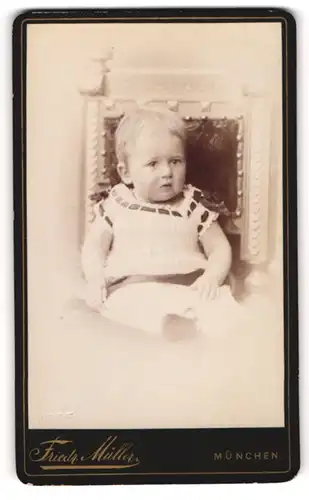 Fotografie Friedrich Müller, München, Portrait niedliches Kleinkind im hübschen Kleid auf Stuhl sitzend