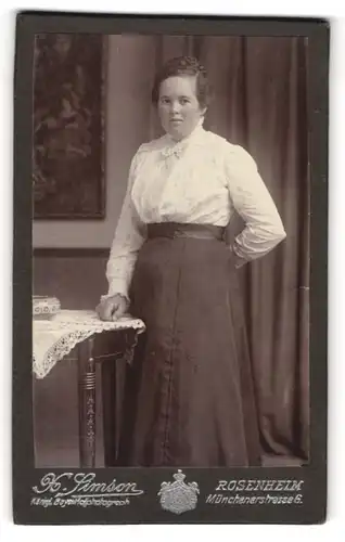 Fotografie X. Simson, Rosenheim, Portrait bürgerliche Dame in weisser Bluse an Tisch gelehnt