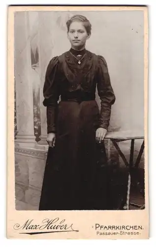Fotografie Max Huber, Pfarrkirchen, Portrait junge Dame im schwarzen Kleid an Tisch gelehnt