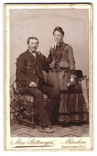 Fotografie Max Stettmeyer, München, Portrait bürgerliches Paar in hübscher Kleidung mit Blumen