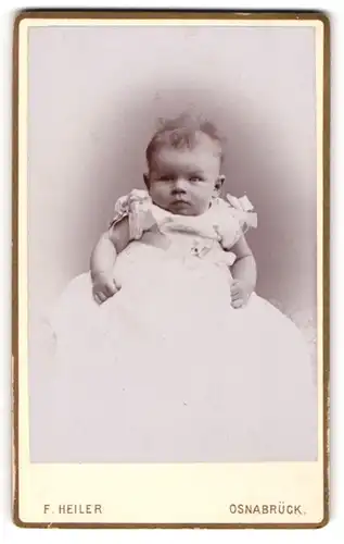 Fotografie F. Heiler, Osnabrück, Portrait niedliches Baby im langen weissen Kleid