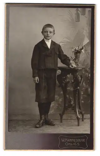 Fotografie W. Hammesfahr, Ohligs, Portrait halbwüchsiger Knabe in hübscher Kleidung an Tisch gelehnt
