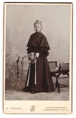 Fotografie J. Fuchs, Berlin-Charlottenburg, Portrait junge Dame im eleganten Kleid mit Blumenstrauss