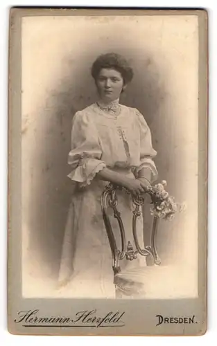 Fotografie Hermann Herzfeld, Dresden, Portrait bürgerliche Dame mit Blumen an Stuhl gelehnt