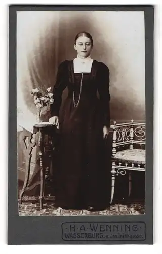 Fotografie H. A. Wenning, Wasserburg a. Inn, Portrait junge Dame im schwarzen Kleid an Tisch gelehnt