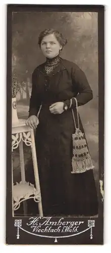 Fotografie H. Amberger, Viechtach i. Wald, Portrait junge Dame im schwarzen Kleid mit Handtäschchen
