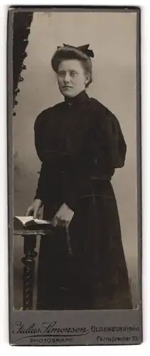 Fotografie Julius Simonsen, Oldenburg i / Holst., Portrait bürgerliche Dame mit Buch an Tisch gelehnt