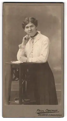 Fotografie Paul Oberst, Oelsnitz i. V., Portrait bürgerliche Dame mit Zeitung an Tisch gelehnt