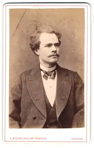 Fotografie C. Michaelsen, Wismar, Portrait junger Herr im Anzug mit Fliege und Schnurrbart