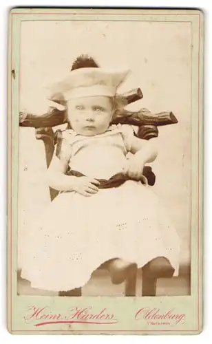Fotografie Heinr. Harders, Oldenburg i / Holstein, Portrait niedliches Kleinkind in hübscher Kleidung auf Stuhl sitzend