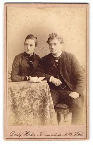 Fotografie Detlef Hahn, Kiel, Portrait elegant gekleidetes junges Paar sitzt an einem Tisch