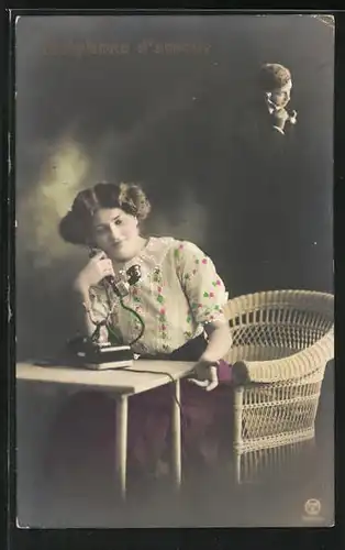 AK junge Frau sitzt mit einem Telefon am Tisch