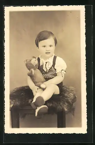 Foto-AK Portrait von einem Kind mit Teddy im Arm auf Fell sitzend