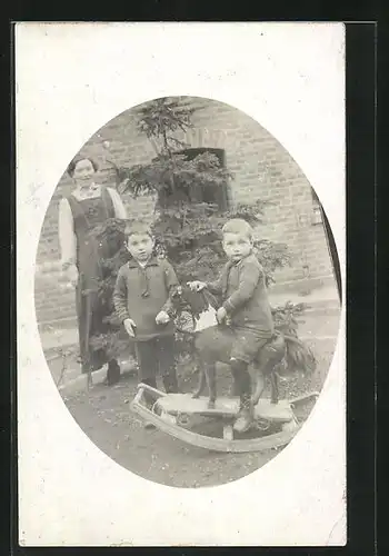Foto-AK Zwei kleine Jungen mit einem Schaukelpferd im Garten