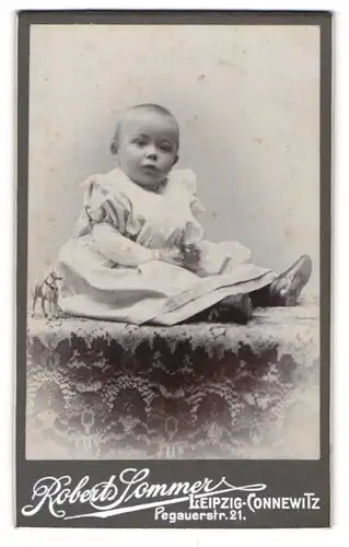 Fotografie Robert Sommer, Leipzig-Connewitz, Portrait niedliches Kleinkind im hübschen Kleid auf Tisch sitzend