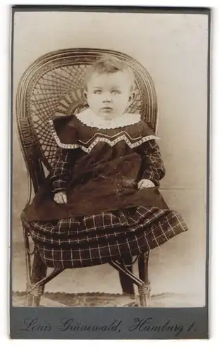 Fotografie Louis Grünewald, Hamburg, Portrait niedliches Kleinkind im hübschen Kleid auf Stuhl sitzend