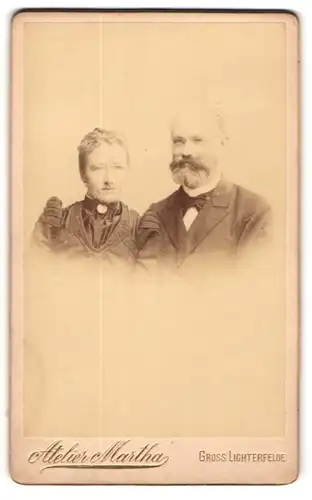 Fotografie Atelier Martha, Gross Lichterfelde, betagter Mann mit Brille & Vollbart nebst seiner Frau mit Halsschmuck