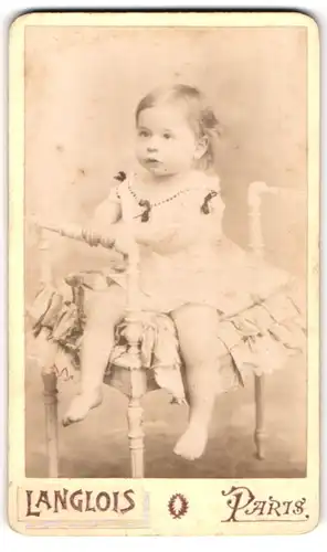 Fotografie Langlois, Paris, Portrait niedliches Kleinkind im Kleidchen auf einem Stuhl sitzend