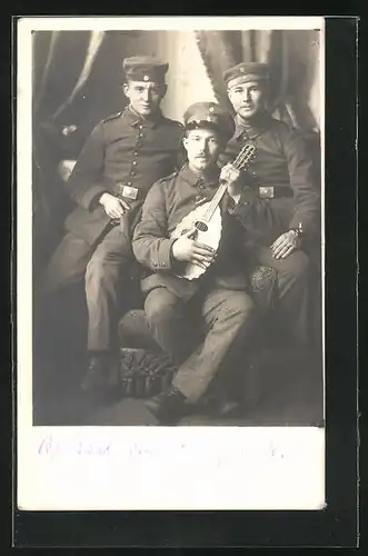 Foto-AK Drei Soldaten in Uniform mit einer Laute an einem Sessel