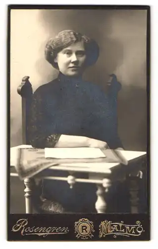 Fotografie Hj. Rosengren, Malmö, Portrait bürgerliche Dame mit Blatt Papier am Tisch sitzend