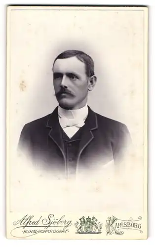 Fotografie Alfred Sjöberg, Karlsborg, Portrait modisch gekleideter Herr mit Fliege und Schnurrbart