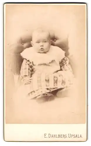 Fotografie E. Dahlberg, Upsala, Portrait niedliches Kleinkind im hübschen Kleid auf Sessel sitzend
