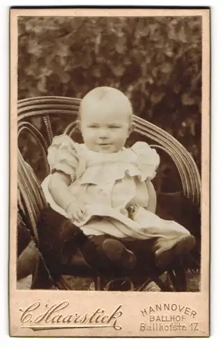 Fotografie C. Haarstick, Hannover, Portrait lächelndes Kleinkind mit Kleidchen im Stuhl sitzend