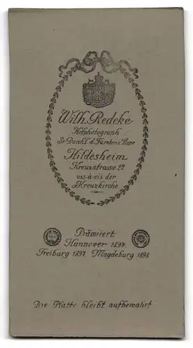 Fotografie Wilh. Redeke, Hildesheim, Portrait bürgerliches Paar in modischer Kleidung am Tisch