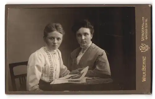Fotografie Wilh. Behne, Verden / Aller, Portrait zwei bildschöne junge Frauen mit Buch am Tisch sitzend