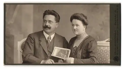 Fotografie Erich Scheithauer, Zwickau i. S., Portrait elegant gekleidetes Paar auf einem Sofa sitzend