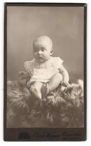 Fotografie Ernst Wagner, Essen-Ruhr, Portrait niedliches Kleinkind im weissen Hemd auf Fell sitzend