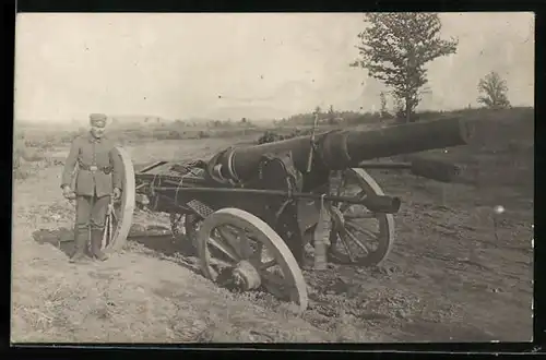 Foto-AK Soldat in Uniform neben im schlamm versacktem 15 cm Geschütz